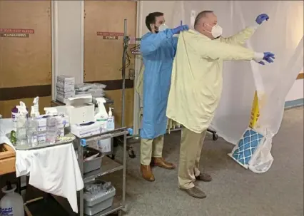  ?? Kyle Mullins/Post-Gazette ?? Dr. Kyle Miller, left, and Sundale Nursing Home medical director Dr. Carl Shrader don personal protective equipment before entering Sundale's COVID-19 isolation wing on Tuesday in Morgantown, W.Va..