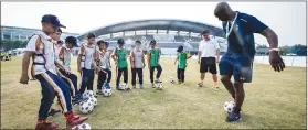  ??  ?? Left: A coach from the Tottenham Hotspur global coaching team trains students in Guangzhou, Guangdong province.