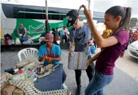  ?? AP ?? A couple looks at a bag made out of Venezuelan bolivars in La Parada, Colombia, on the border with Venezuela. —