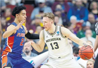  ?? CHARLIE NEIBERGALL THE ASSOCIATED PRESS ?? Michigan forward Ignas Brazdeikis of Mono, Ont., drives around Florida guard Andrew Nembhard, an Aurora native, on Saturday.