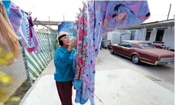  ?? Eric Gay/Associated Press ?? ■ Mickie Subia gathers her laundry Jan. 22 at her home in El Paso, Texas. Subia lives less than a block away from a border barrier that runs along the Texas-Mexico border in El Paso.