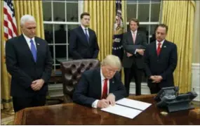  ?? THE ASSOCIATED PRESS ?? President Donald Trump, flanked by Vice President Mike Pence and Chief of Staff Reince Priebus, signs his first executive order on health care Friday in the Oval Office of the White House in Washington.