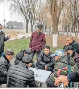  ??  ?? Un grupo de hombres juega a las cartas en un parque de Wuhan.