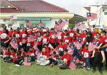  ??  ?? The children join Datuk Ibrahim in raising the Jalur Gemilang at the Grafiti Negaraku event.