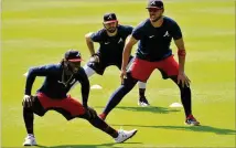  ?? HYOSUB SHIN / HYOSUB.SHIN@AJC.COM ?? Braves second baseman Ozzie Albies (from left), shortstop Dansby Swanson and catcher Tyler Flowers warm up during a Summer Camp workout in Truist Park on July 4.