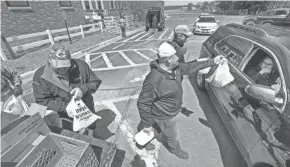  ?? PHOTOS BY MARK HOFFMAN / MILWAUKEE JOURNAL SENTINEL ?? Future Farmers of America Alumni including Dennis Roehl, from left, Adam Luchterhan­d and Tom Odeen hand out free food outside the public schools in Loyal on May 7.