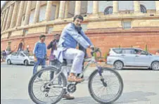  ??  ?? BJP MP Manoj Tiwari arrives for the winter session on a bicycle on Monday; Congress MP Gaurav Gogoi holds placards outside Parliament to protest against air pollution in Delhi.