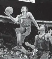  ?? [AP PHOTO] ?? Oklahoma guard Trae Young, left, scores a basket against Arkansas guard Daryl Macon during the first half Thursday at the Phil Knight Invitation­al Tournament in Portland, Oregon.