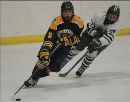  ?? KEN SWART — FOR MEDIANEWS GROUP ?? Clarkston’s Evan Adams (5) carries the puck up ice as Lake Orion’s Jack Kneiding defends during the the OAA Red game played on Thursday at the Detroit Skate Club. The Wolves defeated the Dragons, 3-1.