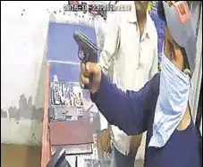  ?? HT PHOTO ?? A video grab showing one of the robbers with a gun inside the money exchanger’s shop in Ludhiana.