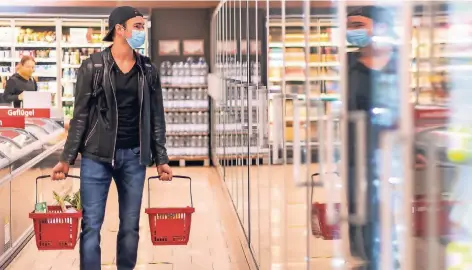 ?? FOTO: ROBERT MICHAEL/DPA ?? Ein Kunde geht in einem Supermarkt einkaufen und trägt dabei einen Mundschutz.