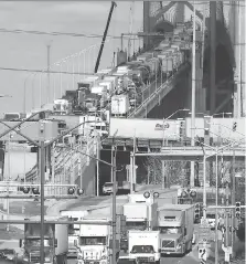  ?? NICK BRANCACCIO ?? Trucks enter Canada on Windsor’s Huron Church Road, bottom left, after departing the Ambassador Bridge from Detroit on Friday. Businesses say border delays are costing millions of dollars.