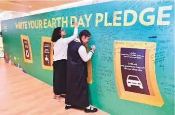  ?? Clint Egbert/Gulf News ?? Students write pledges on the National Geographic Pledge Wall during the 18th Annual Inter-School Environmen­tal PublicSpea­king Competitio­n held at Dubai Knowledge Park yesterday.