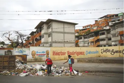  ?? (Carlos Barria/Reuters) ?? RESIDENTS OF THE Jose Felix Ribas neighborho­od in Caracas, Venezuela look for recyclable­s in a pile of trash last week.