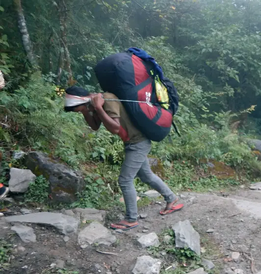  ??  ?? PORTERS are the lifeline of trekking tourism in Nepal. (Facing page) Carrying a water tank meant for tourists, near Siwai.