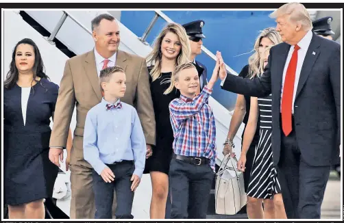  ??  ?? ATTA BOY: President Trump on Wednesday high-fives a boy from a family whose health premiums rose after ObamaCare went into effect.