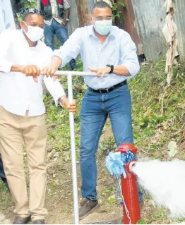  ?? PHOTO BY BRYAN MILLER ?? Prime Minister Andrew Holness (right) is assisted by Hanover Eastern Member of Parliament Dave Brown in opening the valve to allow water to flow through a hydrant in the community of Claremont during the commission­ing of the Claremont-to-Jericho water-supply system on Saturday.