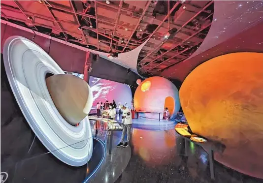  ?? — Photos by Wang Rongjiang ?? Visitors “walk in the solar system” at the Shanghai Astronomy Museum, which opened for a trial run on Monday, with immersive experience­s of the Earth, moon, sun and other planets. The museum, said to be the largest in the world, officially opened to the public on July 18.