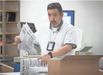  ?? MARK HENLE/THE REPUBLIC ?? Gary Ramirez processes ballots on Wednesday at the Maricopa County Tabulation and Election Center in Phoenix. As of Thursday night, thousands of ballots remained to be tabulated.