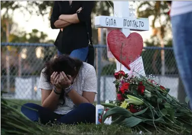  ?? MARK WILSON — GETTY IMAGES ?? Kareen Vargas bows her head while visiting a makeshift memorial in front of Marjory Stoneman Douglas High School, where 17 people were killed on Feb. 14, 2018, in Parkland, Florida.