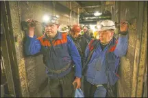  ??  ?? Miners hold bags of food as they stand in an elevator taking them undergroun­d.