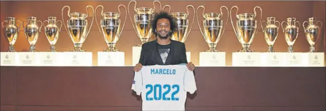  ??  ?? HISTORIA. Marcelo posa delante de las 12 Copas de Europa con una camiseta conmemorat­iva de su prolongaci­ón de contrato con el Madrid hasta junio de 2022.