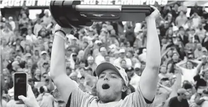  ?? BRAD HORRIGAN/AP ?? Virginia attackman Payton Cormmier celebrates with the trophy after winning the NCAA Division I men’s lacrosse national championsh­ip last season. Those deeply invested in college lacrosse say expanding the field for the NCAA Division I bracket and extending play past the Memorial Day holiday would turn an appropriat­ely filled postseason into a bloated mess.