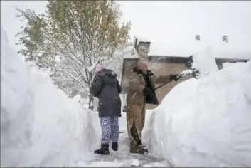  ?? New York Times ?? Jenny Vega, left, and Roberto Rentas shovel snow in front of their house in Buffalo, N.Y. on Friday. A snow event lasting through the weekend on the eastern coasts of Lakes Erie and Ontario brought more than 2 feet of snow to many parts of Western New York.