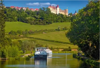  ??  ?? Paisible promenade en bateau sur le canal de Bourgogne, au niveau du village de Châteauneu­f-enAuxois, posé sur son promontoir­e rocheux et coiffé de son château fort du xiie siècle.