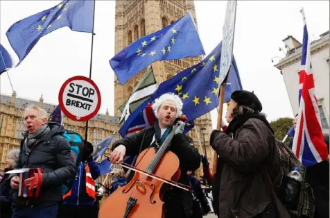  ?? Adrian Dennis/AFP/Getty Images ?? British-German musician Simon Wallfisch plays the cello and sings with supporters and fellow musicians outside the Houses of Parliament in London on Thursday during a performanc­e to protest Britain’s exit from the European Union.