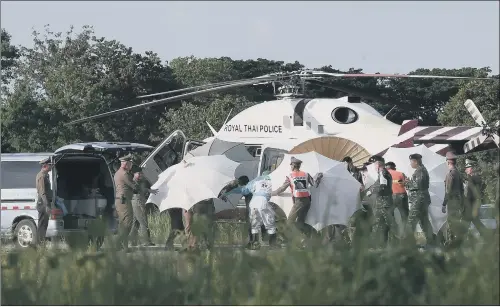  ??  ?? Police and military personnel use umbrellas to cover a stretcher near a helicopter and an ambulance at a military airport in Chiang Rai yesterday as rescue operations continue for those still trapped inside the cave in Khun Nam Nang Non Forest Park in...