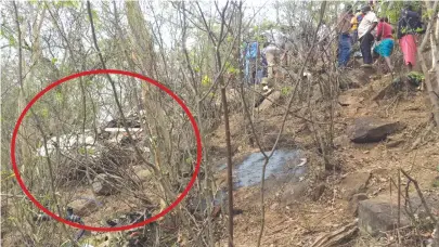  ??  ?? Curious onlookers view the wreckage (encircled) of the Cessna that crashed near Renco Mine in Masvingo yesterday