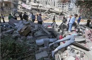  ?? AFP photo ?? Residents gather in front of a clothing shop in Gaza city that was damaged during Israeli air strikes.—