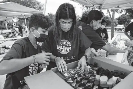  ?? Photos by Yi-Chin Lee / Staff photograph­er ?? Volunteers Dean Ramzi, 10, and Komal Premjee sort a box of hygiene products during a supply drive for Afghan refugees and survivors of the earthquake in Haiti at the Ismaili Jamatkhana and Center in Sugar Land on Saturday.