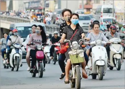  ?? HOANG DINH NAM / AFP ?? Motorcycli­sts ride at rush hour on a street in downtown Hanoi last year. Officials in Vietnam’s traffic-choked capital vowed last July to banish motorbikes by 2030 to ease environmen­t and congestion woes, but a new report has found that air quality in...