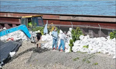  ?? CHARLIE NEIBERGALL/AP PHOTO ?? Workers build a sandbag wall Monday on a levee near the Cedar River in Cedar Rapids, Iowa.