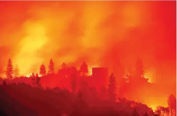  ?? AFP photo ?? File photo shows flames from the Camp fire burn near a home atop a ridge near Big Bend, California.—