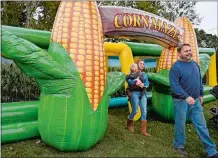  ?? SARAH GORDON/THE DAY ?? Brooke Praskievic­z carries her nephew Thomas, 2, as they follow her father, Tom, out of the inflatable corn maze at the Pumpkin Palace at The Dinosaur Place at Nature’s Art Village.