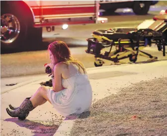  ?? JOHN LOCHER, THE ASSOCIATED PRESS ?? A woman sits on a curb after the attack at a country music festival in Las Vegas that killed 58 people and injured hundreds on Oct. 1.