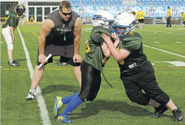  ?? LARRY WONG ?? Edmonton Eskimos’ Matt O’Donnell watches two young football players during a drill at the annual Eskimos Amateur Football Camp at Clarke Field. The camp lets players ages nine to 12 to learn from CFL players and university and junior football coaches.