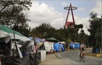 ?? AP PHOTO/JAE C. HONG ?? A cyclist passes the row of tents and tarps along the Santa Ana riverbed near Angel Stadium, Thursday, in Anaheim. Amid an uproar from residents, the city of Anaheim declared an emergency Wednesday in an attempt to cope with a ballooning homeless...