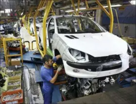  ?? EBRAHIM NOROOZI — THE ASSOCIATED PRESS FILE ?? An Iranian worker assembles a Peugeot 206 at the state-run Iran-Khodro automobile manufactur­ing plant near Tehran, Iran.