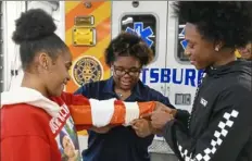  ?? Darrell Sapp/Post-Gazette photos ?? Janiya Beasley, a junior at Westinghou­se Academy, holds up her arm as junior Raynne Jenkins ties a splint and senior Marquise Middleton assists Wednesday at the school in Homewood.