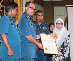  ??  ?? WAN Mohd Noor menyampaik­an anugerah kepada Azieana Farhana yang mewakili arwah Abu Zarin.