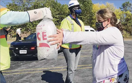  ?? Lori Van Buren / Albany Times Union ?? A National Grid worker on Friday hands ice to Maggie Padilla of Delmar at a Crossgates Mall parking lot, where the line for dry ice went on and on.