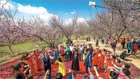  ?? YUAN HUANHUAN / FOR CHINA DAILY ?? Residents of Aksu in the Xinjiang Uygur autonomous region dance with tourists in a local garden in March.