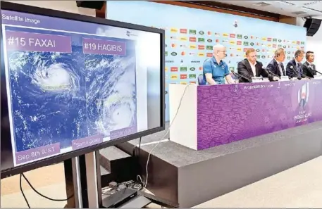  ?? WILLIAM WEST/AFP ?? Tournament director of the Japan 2019 Rugby World Cup Alan Gilpin (2nd left) speaks to the media in Tokyo on Thursday as a screen shows the the path of the approachin­g typhoon Hagibis, which will affect upcoming World Cup matches.