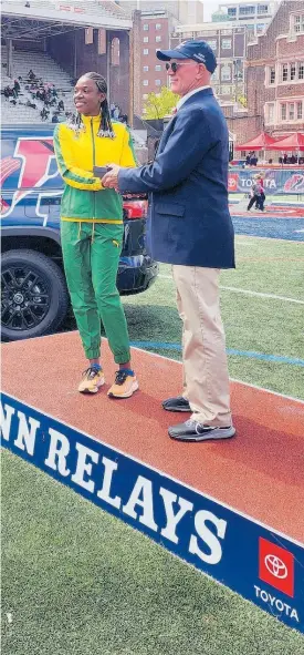  ?? RAYMOND GRAHAM ?? St Jago High’s Jade-Ann Dawkins (left) collects a Penn Relays commemorat­ive watch on Thursday for winning the high school girls’ Championsh­ips of America triple jump with 13.01 metres to defend her title.