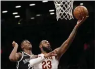  ?? KATHY WILLENS — ASSOCIATED PRESS ?? Nets guard Caris LeVert defends LeBron James as James goes up for a layup during the first half.