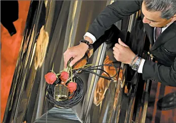  ?? FERNANDO LLANO/AP ?? A mourner places roses on crooner Jose Jose’s casket during a memorial Wednesday in Mexico City. It was agreed after a dispute among relatives that half the ashes would remain in South Florida, where he died, and the other half would be brought to Mexico.